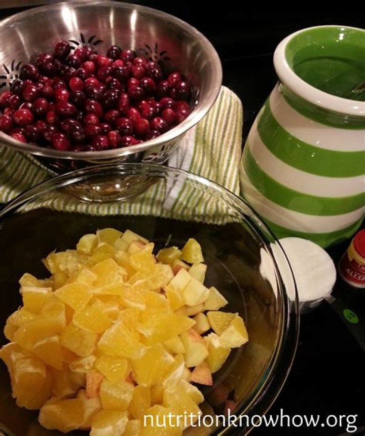 Oranges, apples, cranberries, and sugar in a food processor.